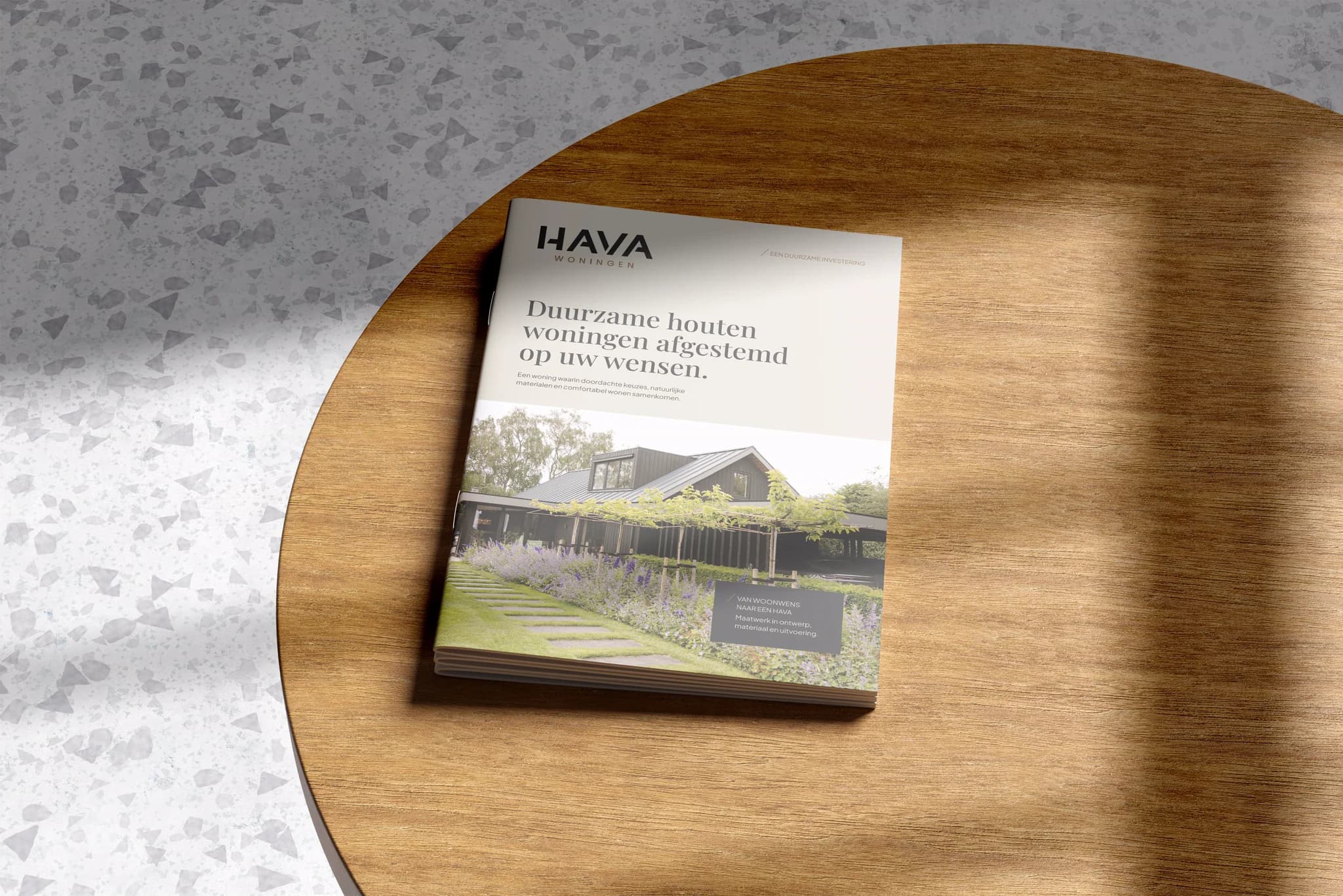 Gids van HAVA Woningen met informatie over duurzame houten woningen op een ronde houten tafel.