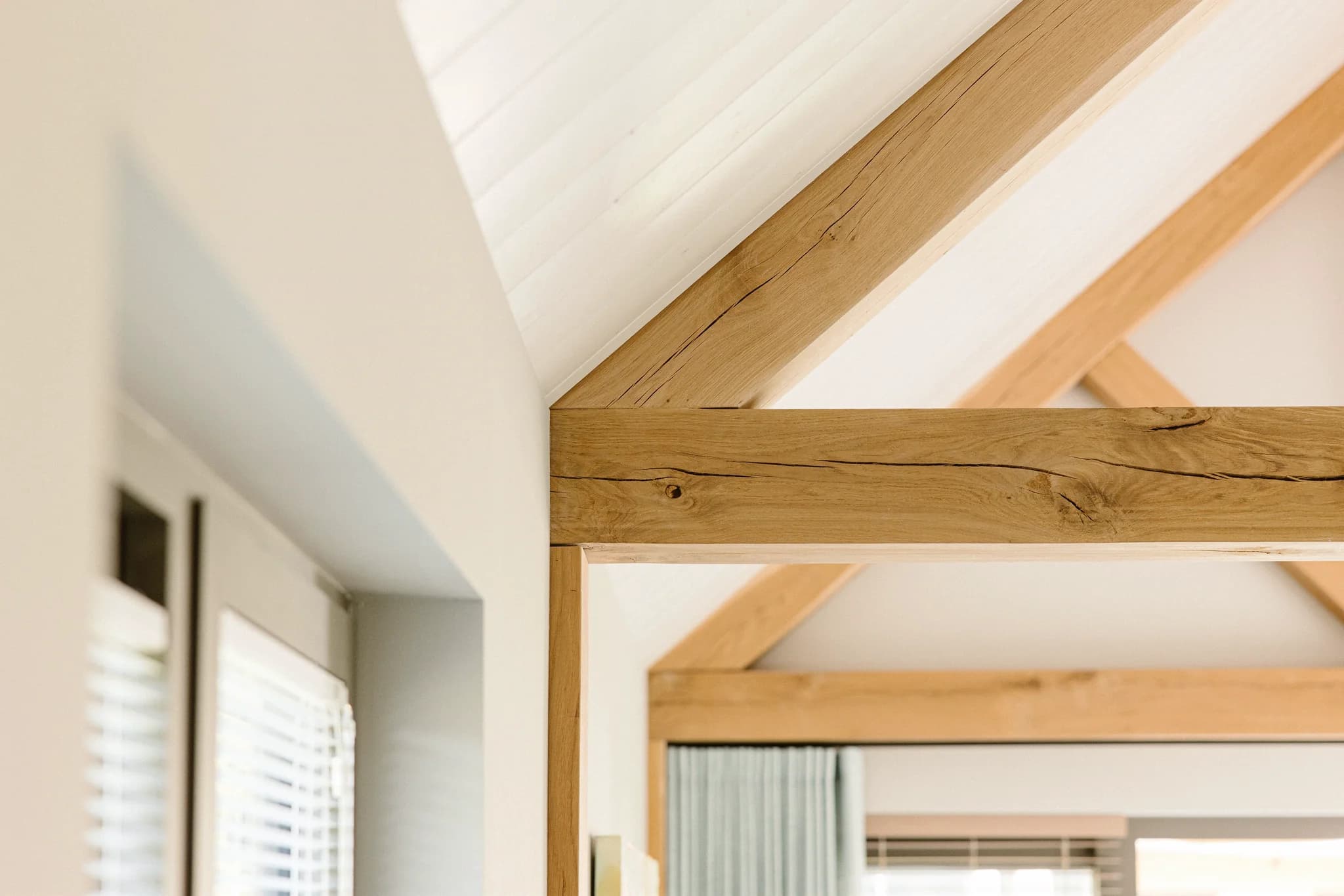 Houten balken en lichtkoepel in een modern interieur met witte muren en groene gordijnen