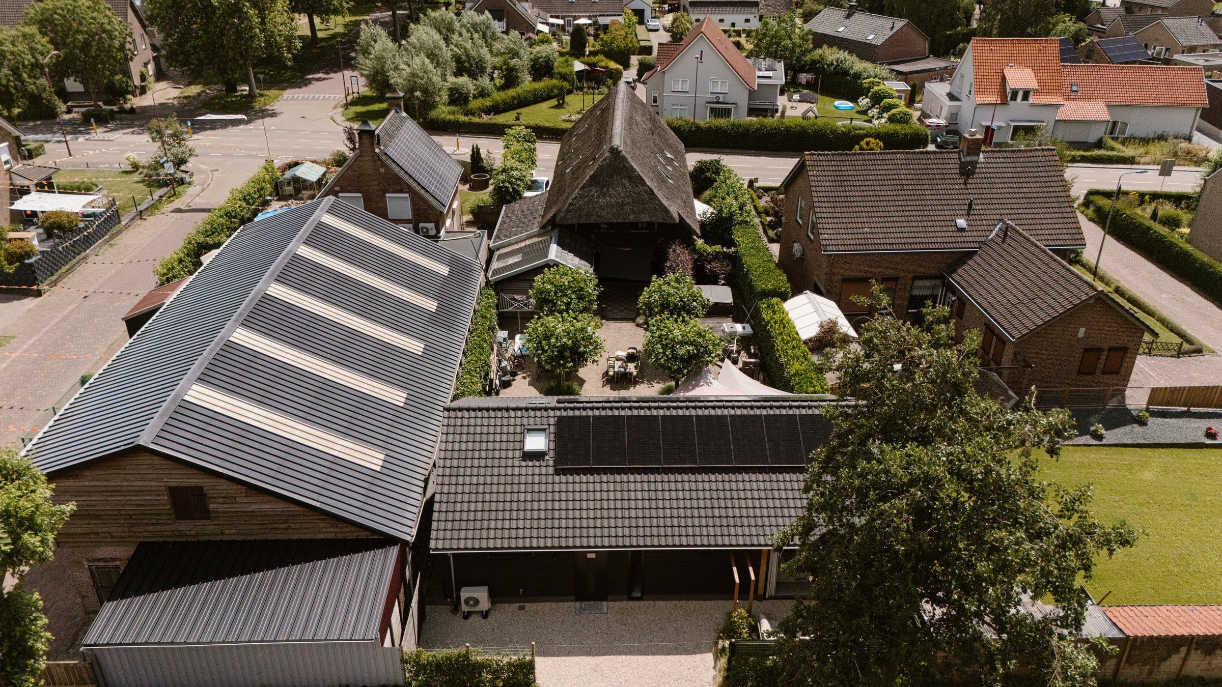 Luchtfoto van meerdere huizen met zonnedaken en tuinen in een woonwijk