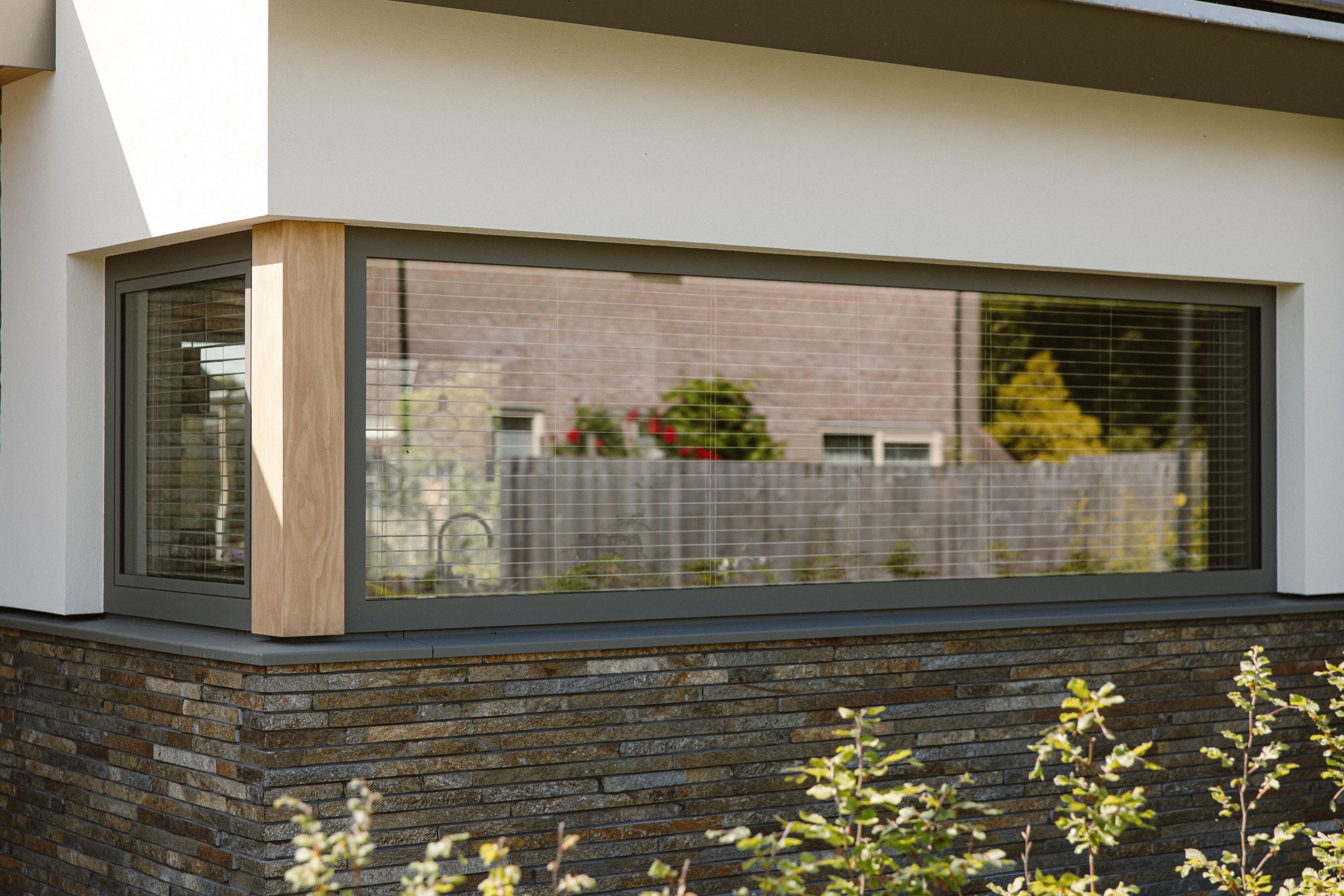 Witte hoekwoning met grote glazen ramen en beschoeiing van steenstrips