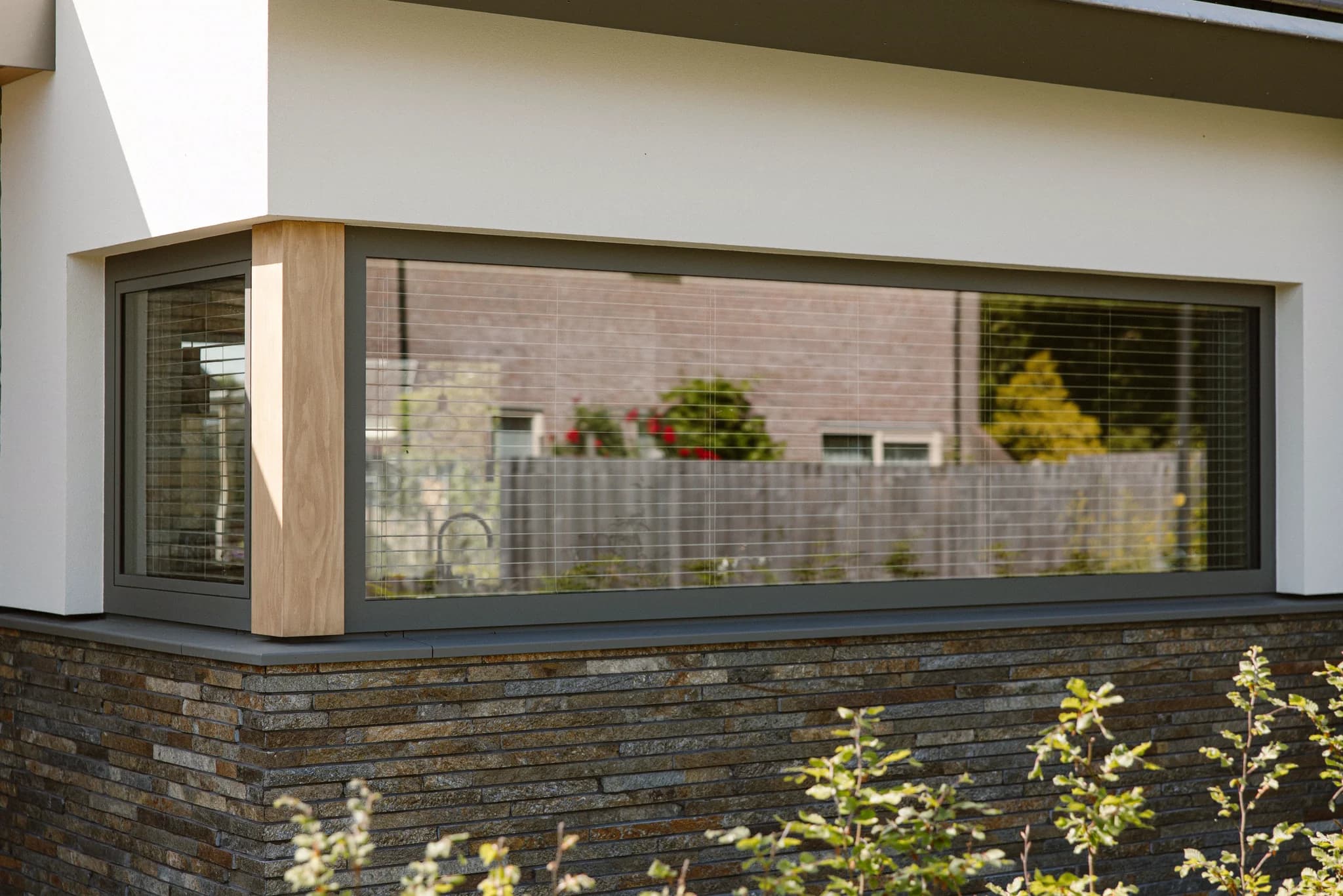 Witte hoekwoning met grote glazen ramen en beschoeiing van steenstrips