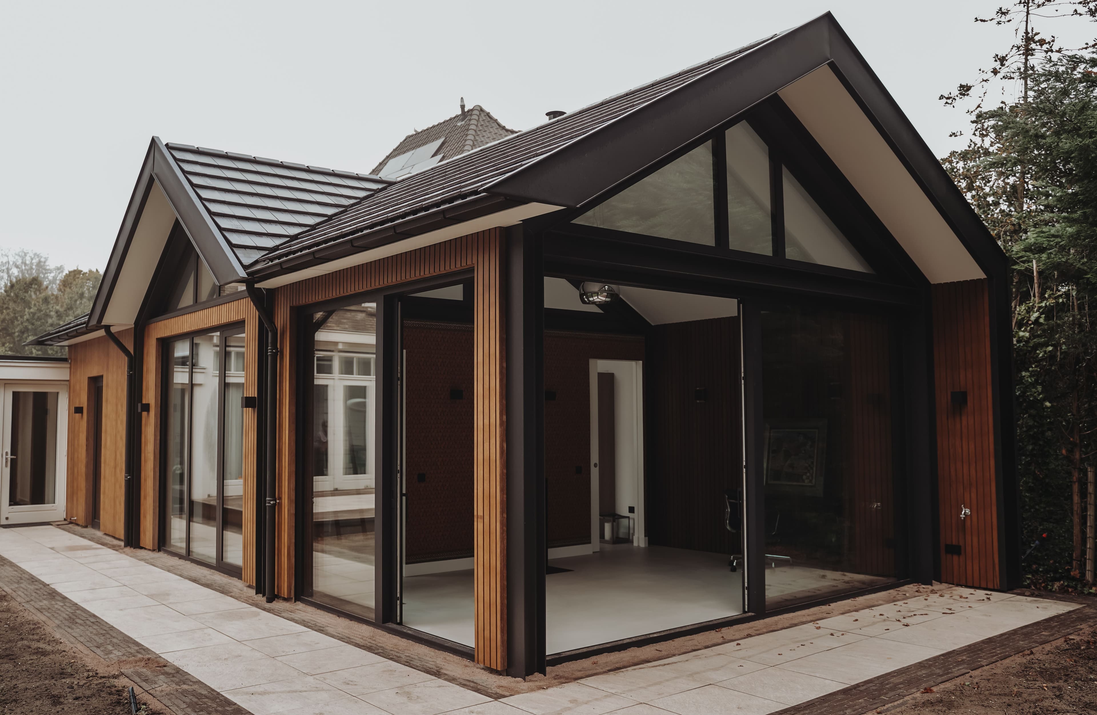Moderne buitenruimte met houten gevelbekleding en grote glazen schuiframen