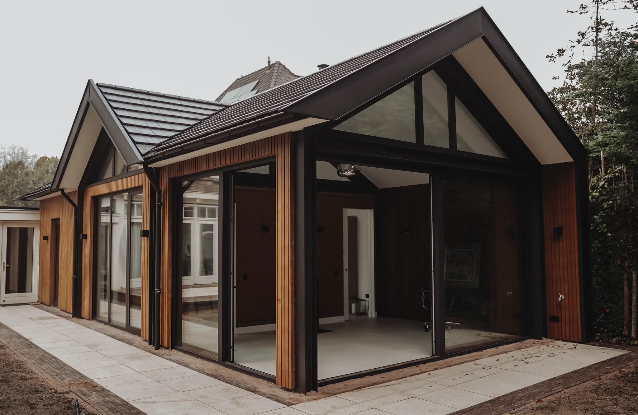 Moderne buitenruimte met houten gevelbekleding en grote glazen schuiframen