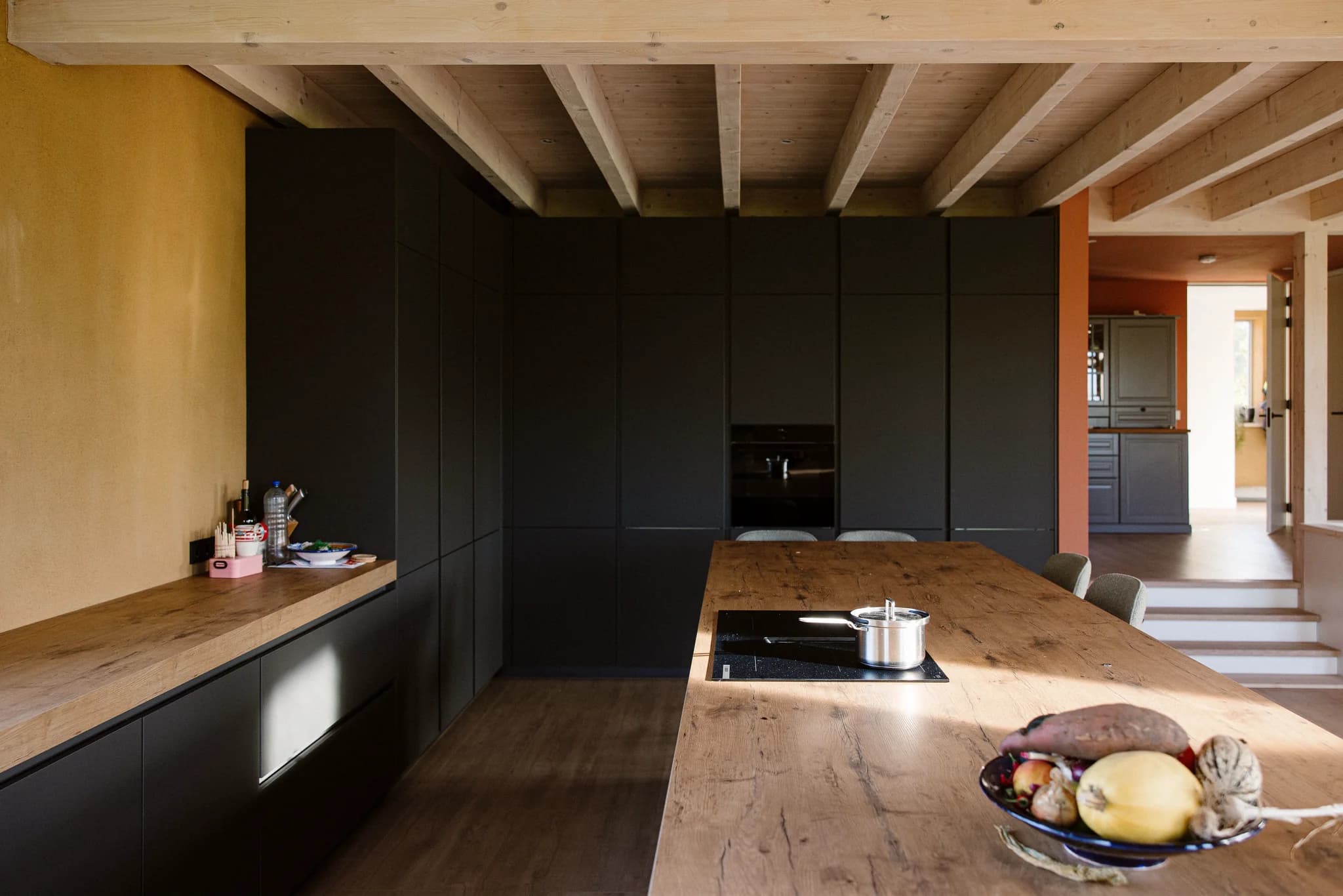 Interieur van een moderne keuken met zwarte kasten, houten werkbladen en een kookplaat in het keukeneiland