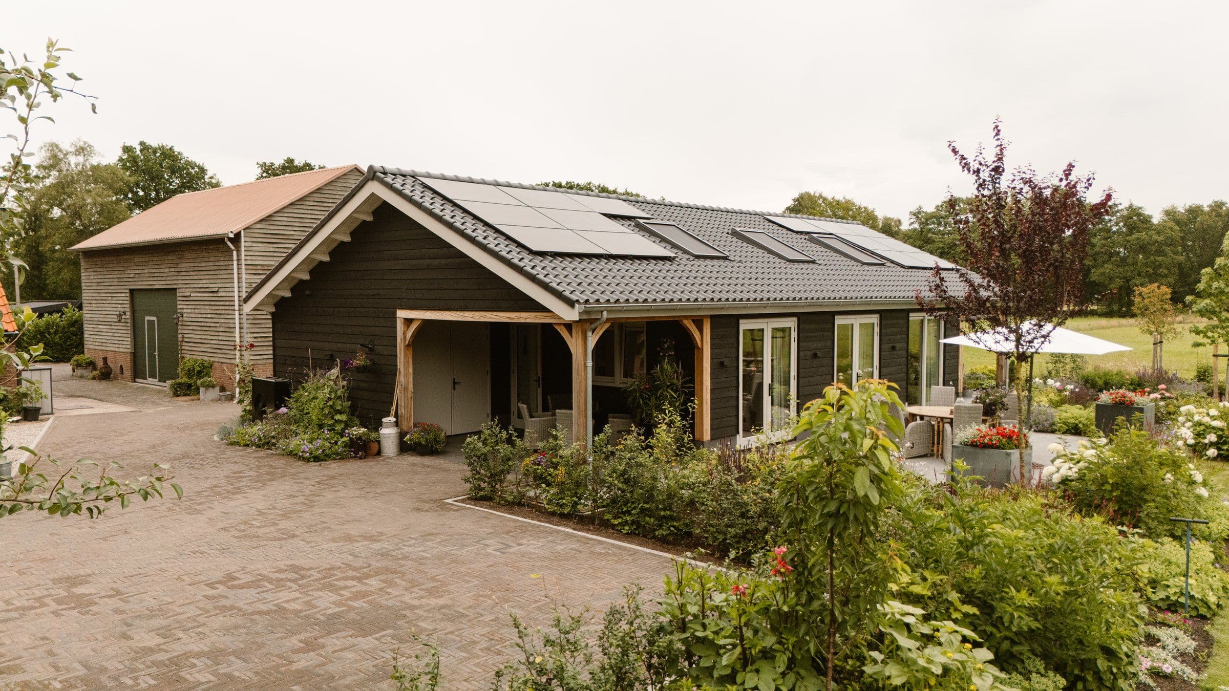 Woonboerderij met zonnepanelen op het dak, tuin en zitgedeelte met parasol buiten