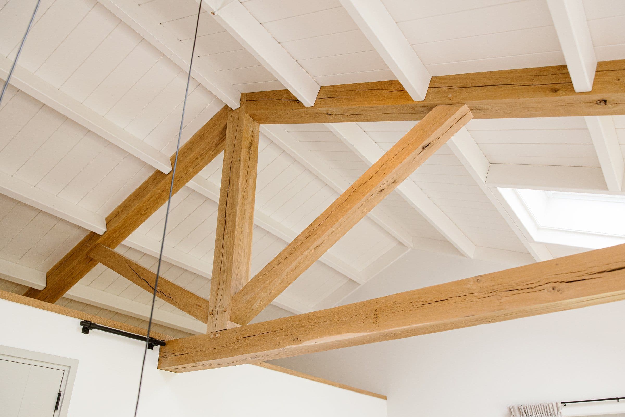 Witte zolder met houten balkenstructuur en dakraam