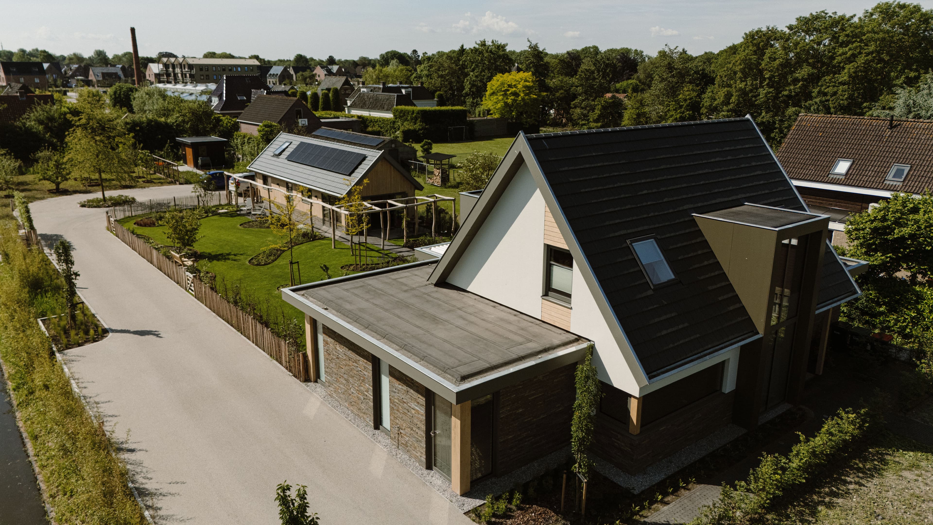 Luchtfoto van moderne woningen met groene tuinen en een rustige straat