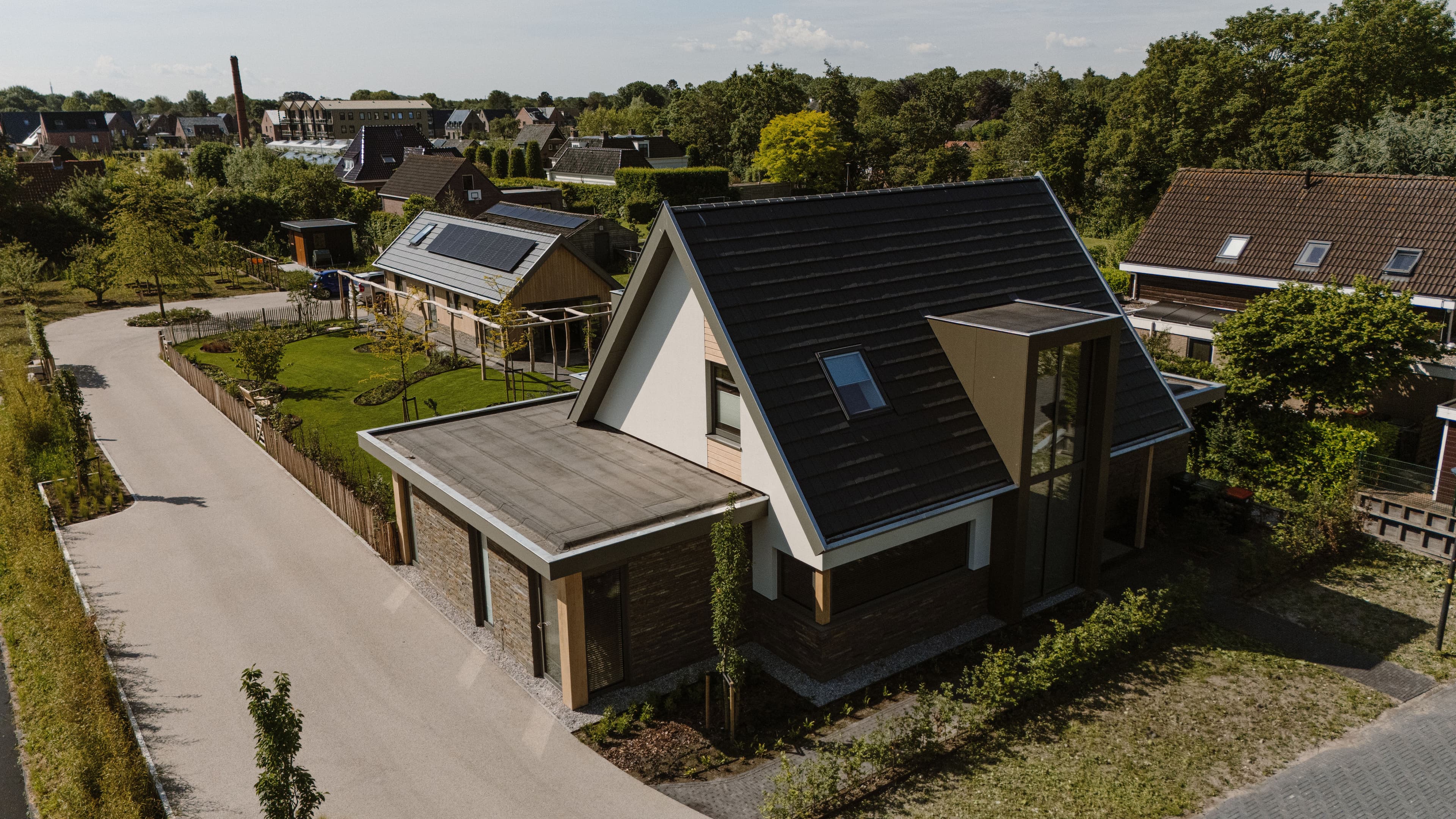 Luchtfoto van een woonstraat met huizen, tuinen en zonnepanelen op een dak