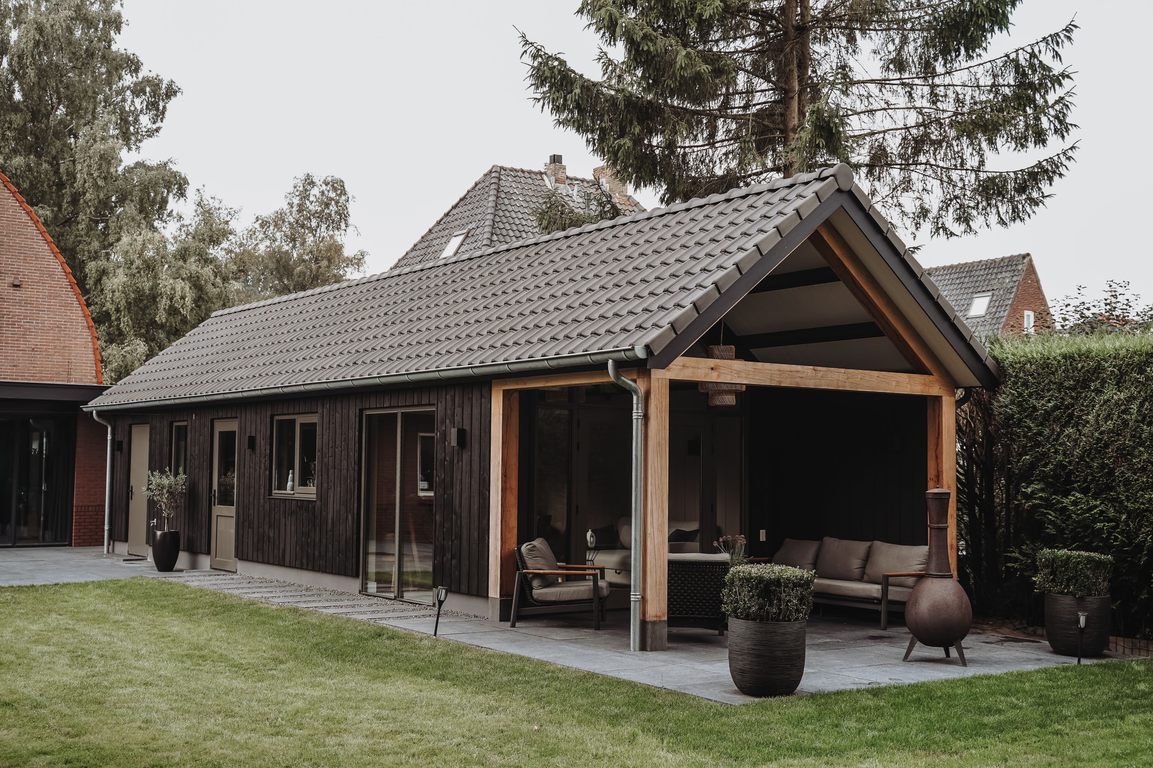 Moderne houten tuinwoning met glazen schuifdeuren en overdekt terras met tuinmeubilair