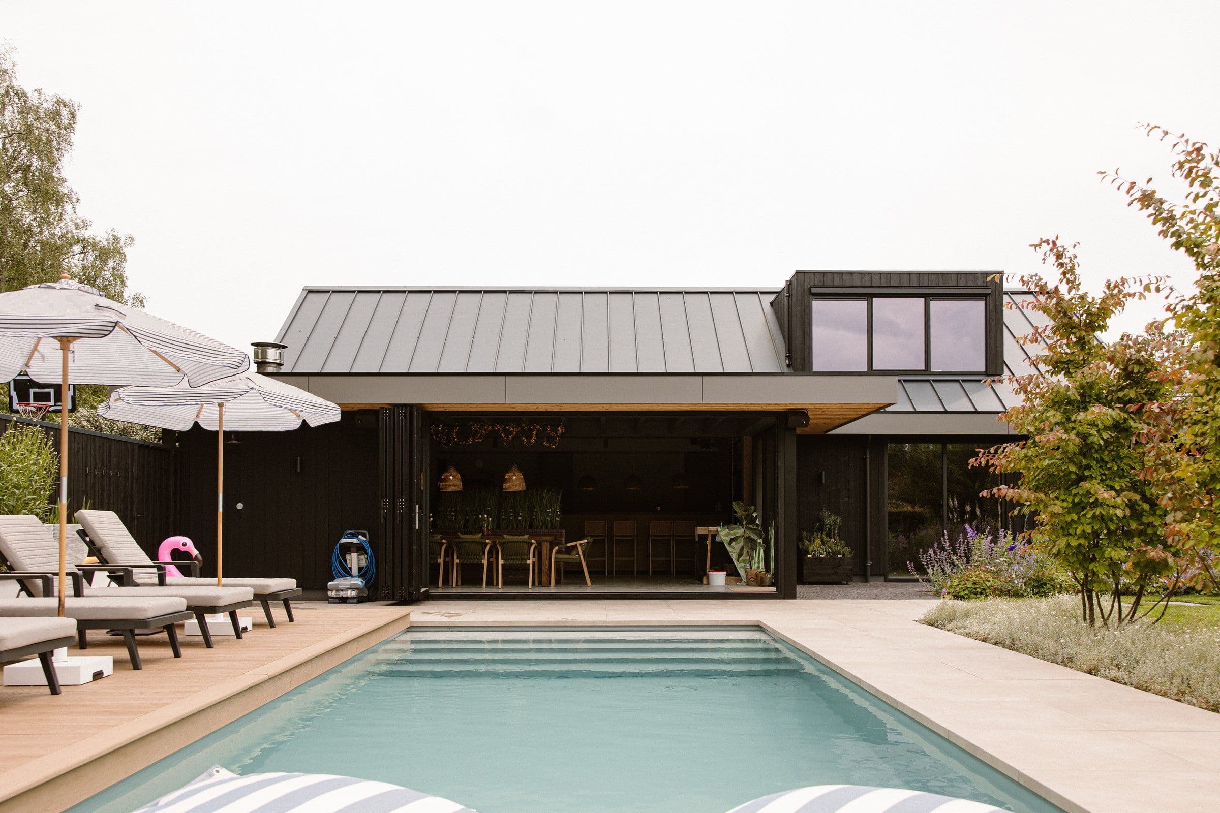 Zwembad met ligstoelen en parasols voor een moderne woning met grote ramen